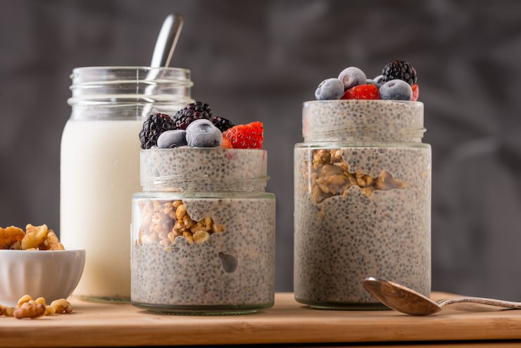 Thick Indian style yogurt chia pudding in a steel katori topped with crushed almonds and pistachios.
