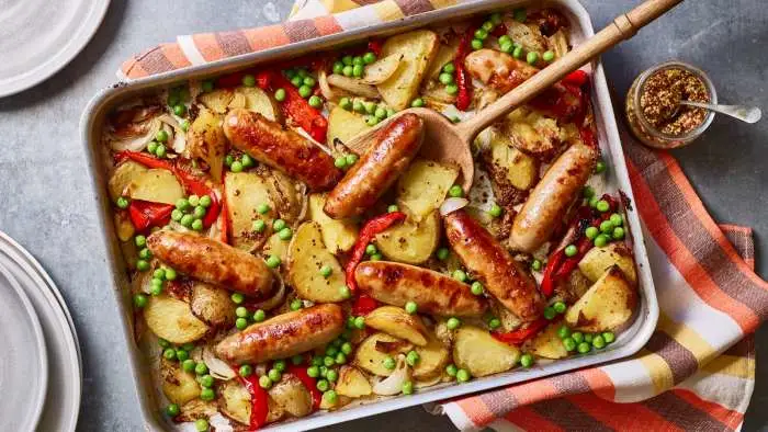 Sticky sausage and potato traybake with rosemary and red onion served in a large roasting dish. Sticky sausage and potato traybake with rosemary and red onion served in a large roasting dish.