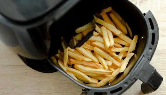 Golden crispy French fries in an air fryer basket Golden crispy French fries in an air fryer basket