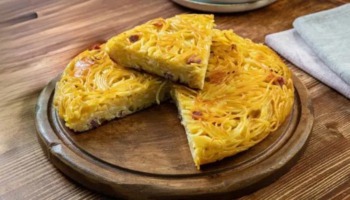 A crispy, golden slice of Italian pasta frittata served on a rustic plate. A crispy, golden slice of Italian pasta frittata served on a rustic plate.