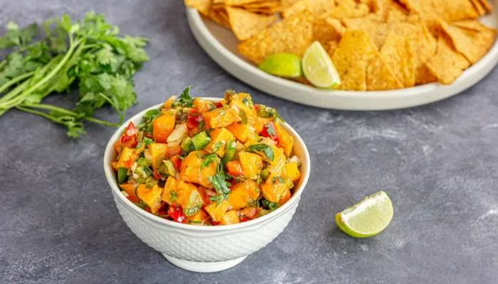 Close-up of a bowl of fresh homemade mango salsa with chopped red peppers, lime, and tortilla chips. Close-up of a bowl of fresh homemade mango salsa with chopped red peppers, lime, and tortilla chips.